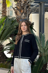 a lady in a black knit top and a pair of white pants